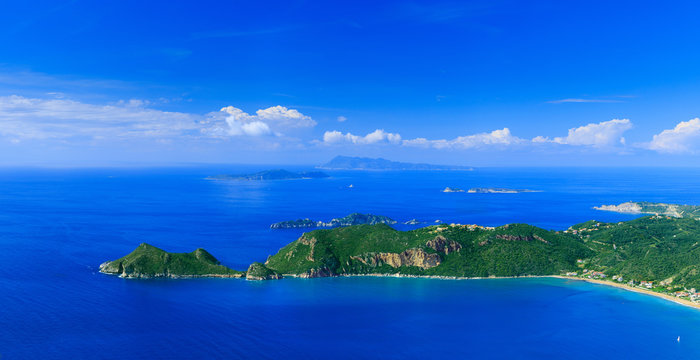 Beautiful summertime panoramic seascape. View of the cliff into the crystal clear azure sea bay and distant islands. Agios Stefanos cape. Afionas. Corfu. Greece.