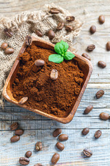Wooden bowl with ground coffee, mint and coffee beans.