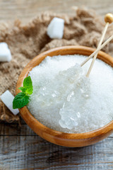 Sticks with crystal white sugar in a wooden bowl.