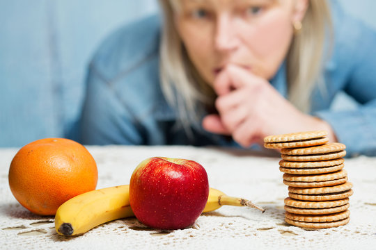 Woman Choosing Between Fruit And Sweets