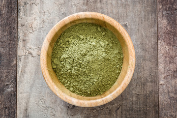 Matcha green tea in a bowl, on wooden background
