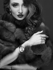 Luxury elegant woman in fur coat, golden earrings and watches. Glamour beautiful look. Rich lady...