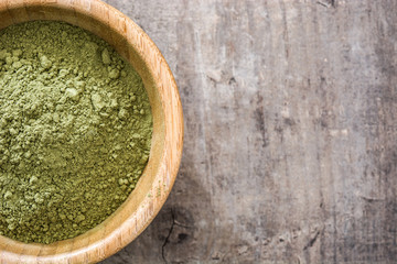 Matcha green tea in a bowl, on wooden background
