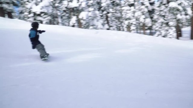4k Boy snowboarding for the first time. shot from another snowboarder parallel track 