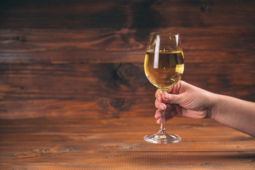 Woman hand cheering with glasses of white wine against wooden background