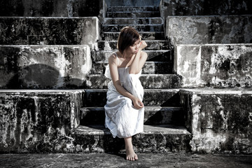 woman in frustrated depressed sitting on stairs, crying and contemplating suicide, in scary abandoned building, Concept of unemployed, sadness, depression, broken heart and human problem in dark tone.