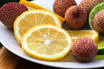 Fototapeta na wymiar Fresh fruits - Lime, Lemon, Litchi in a white plate