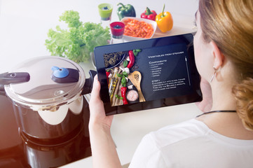 Woman checks the recipe on her tablet.