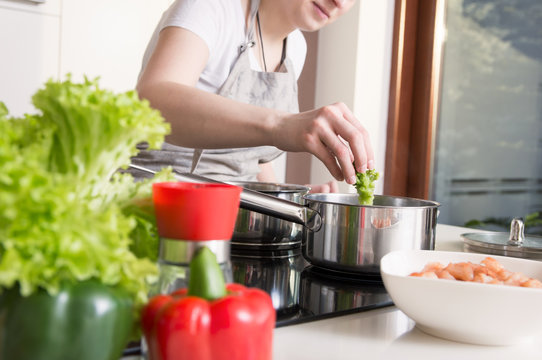 Woman puts vegetables into the pot. Conception of healthy food preparing.