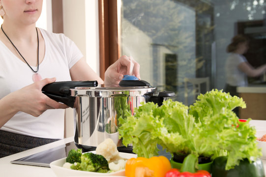 Woman uses pressure cooker to cook a meal. Conception of healthy nutrition.