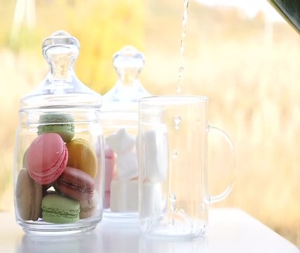 Cup of mint tea with macaroons and marshmallows. Beautiful sunny day in spring. Green and yellow background. French bakery with hot tea. Tasty breakfast, spring mood. 
