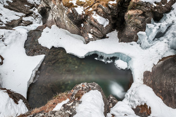 Saent waterfall, located in Val di Rabbi, Trentino Alto Adige, almost entirely covered by snow. Blue sky with few clouds