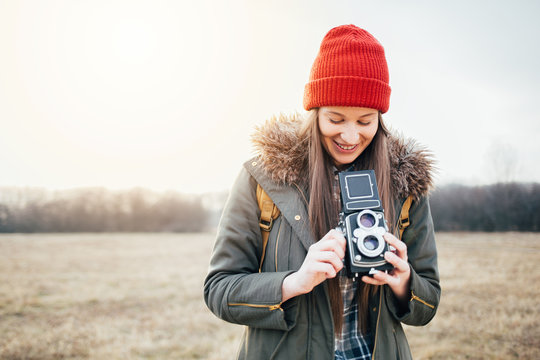Smiling hipster girl taking photo with vintage camera