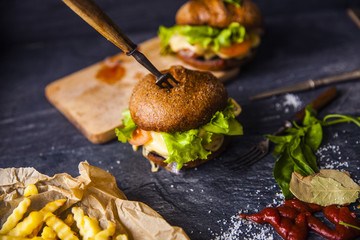 Fast food on the table: burger with beef or pork, or chicken and vegetables, French fries with tomato sauce, basil leaves