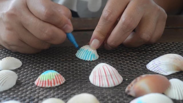 Coloring shells on table. Creative process. Girl paint on shells by hand