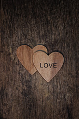 Two wooden hearts with text "love" on dark rustic wooden texture background. heart, symbol of romance, love. Valentine's day, 14 february holiday concept. flat lay