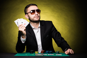 Man with four aces in hands playing on table in casino