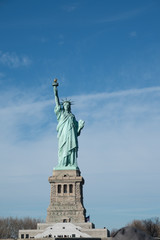 Obraz premium Lady Liberty on her pedestal. Statue of Liberty overlooking New York Harbor on a sunny day with blue skies and wispy clouds. Liberty Island, New York City, USA.
