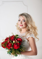 Portrait of beautiful bride with bouquet, gorgeous blonde bride with curly hairstyle in vintage white lace wedding dress holding red peonies bouquet, sensual look, fairytale woman