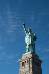 Obraz premium Statua Wolności na piedestale z błękitnym niebem i cienkimi chmurami, Liberty Island, Nowy Jork, USA w jasny słoneczny zimowy dzień. Żadnych ludzi. Lady Liberty spoglądająca w stronę portu w Nowym Jorku.