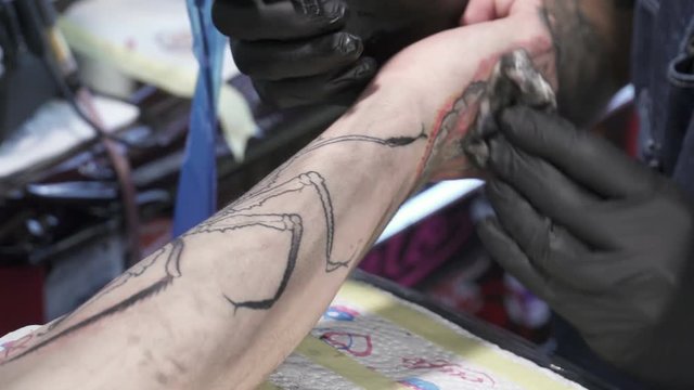 Closeup of a tatooer coloring tatoo on man's hand