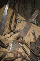 Many old rusty tools scattered on the wooden tstolu. View from above.