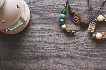 handmade colorful beads on a black thread lie on a wooden table with a natural white candlestick