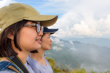 Face two young women hiker, mother and daughter smiling happily while looking beautiful landscape...