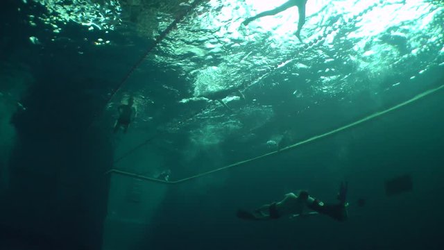 Underwater wrestlers and swimmers are training in the pool, wide shot.
