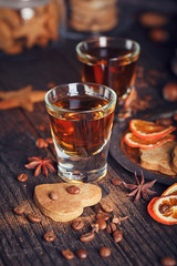 Whiskey or liqueur, cookies, spices and decorations on wooden background.
