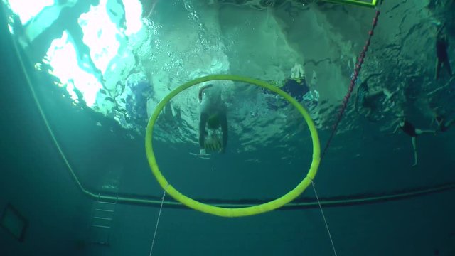 Underwater wrestler in the yellow cap begins to fight, passing through the ring installed under water.
