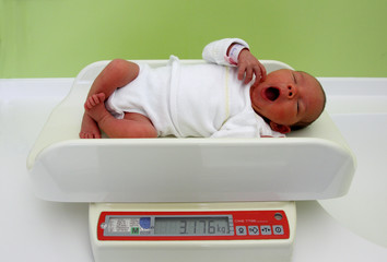 Ein Baby liegt auf einer Waage in einem Familienzimmer im Krankenhaus.
