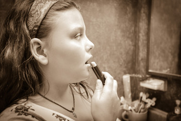 Nice amazing monochrome view of a little girl holding lipstick and doing make up on her face