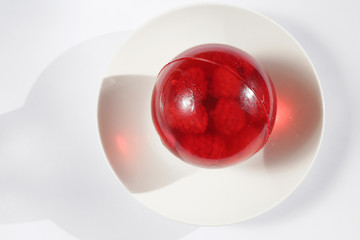 round  raspberry jelly with raspberries on a white plate on a light background