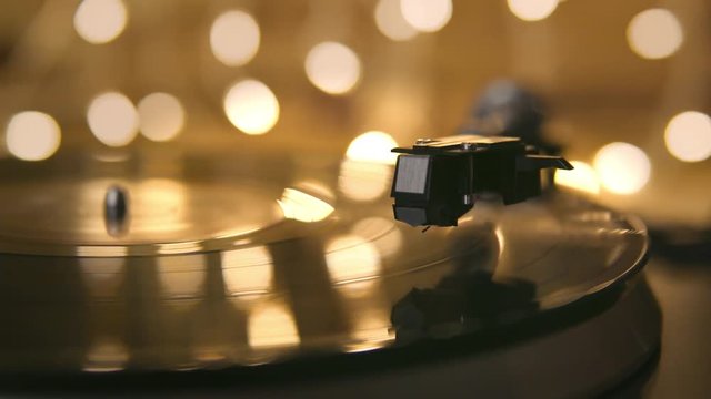 Gramophone and record to listen to. Included gramophone and torque plate close-up on a light background with bright lights. Hand puts needle on vinyl record