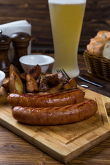 hot sausages serving on wooden board with beer