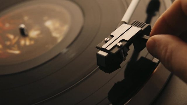 Gramophone and record to listen to. Included gramophone and torque plate close-up on a light background with bright lights. Hand puts needle on vinyl record