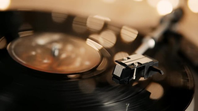 Gramophone and record to listen to. Included gramophone and torque plate close-up on a light background with bright lights. Hand puts needle on vinyl record