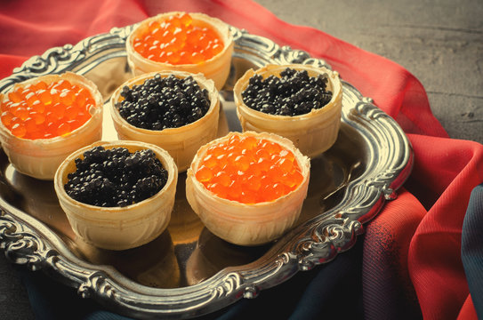 Black and red caviar tartlets, appetizer canapes on silver tray