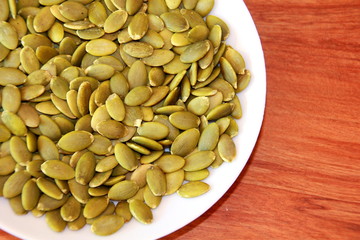 Green pumpkin seeds on a white plate