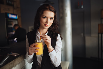 Healthy eating - portrait of young woman keeping orange juice at restaurant bar