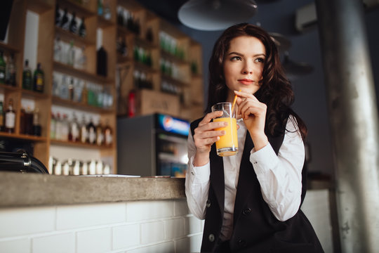 Healthy eating - young woman keeping orange juice at restaurant bar