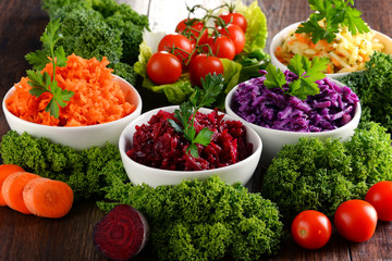 Composition with four vegetable salad bowls on wooden table