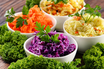 Composition with four vegetable salad bowls on wooden table