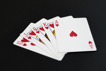 Royal Flush of hearts in poker cards game on a black background