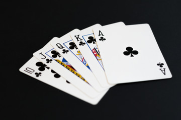 Royal Flush of clubs in poker cards game on a black background