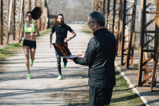 Coach Staff Of Running With  Laptop And 2 Runners