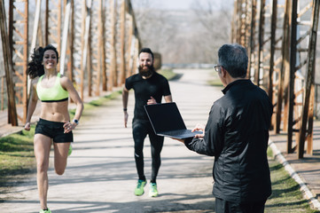 coach staff of running with  laptop and 2 runners