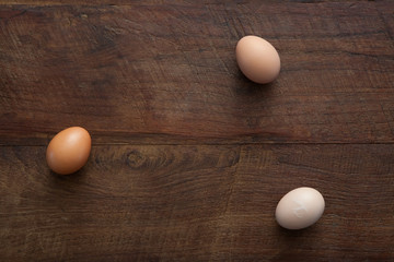Three Farm Fresh Chicken Eggs Horizontal Flat Lay on Brown Rustic Wooden Farm Table