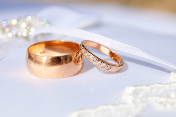 Obraz na płótnie Canvas couple of gold wedding diamond rings on white wedding pillow